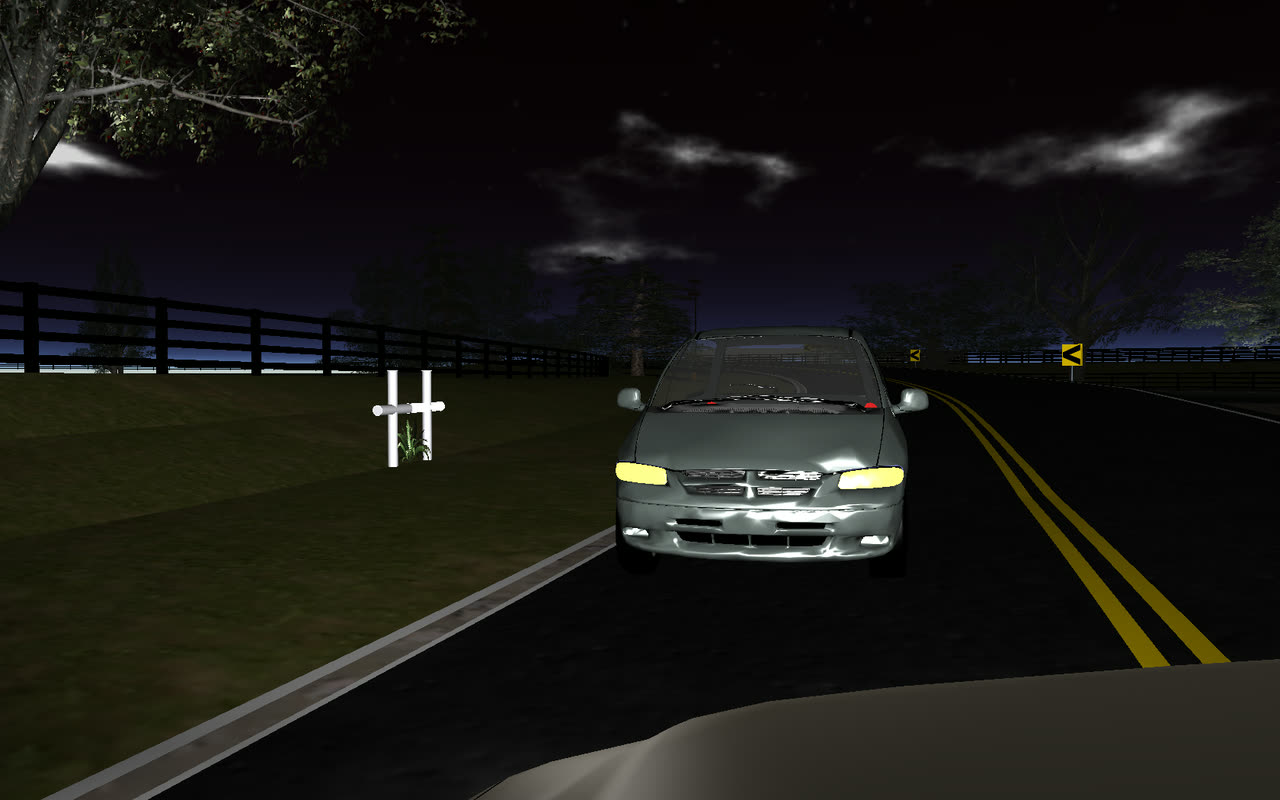 Driver's-eye view approaching a minivan on a dark rural road in a nighttime visibility study